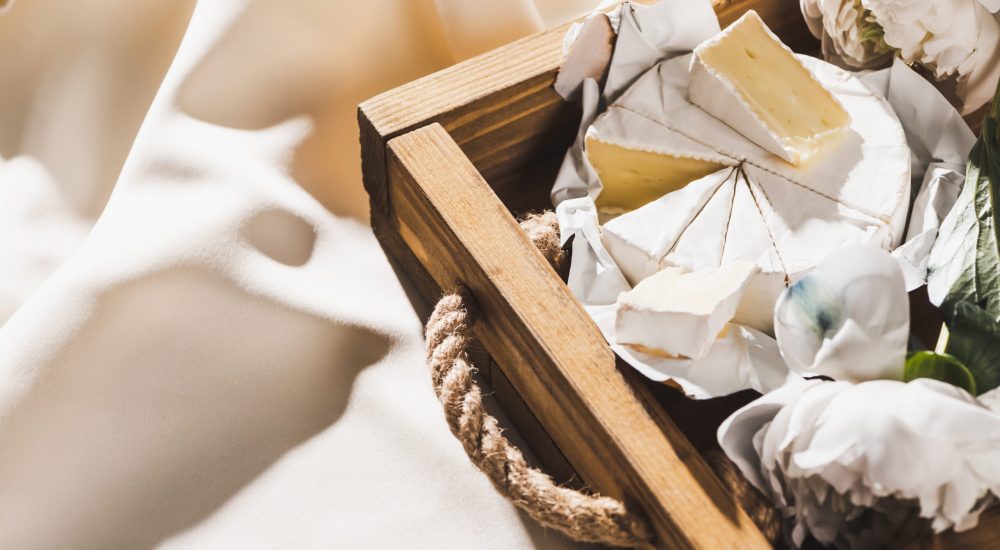 Close up View of French Breakfast With Camembert on Wooden Tray on Textured White Cloth With Peonies